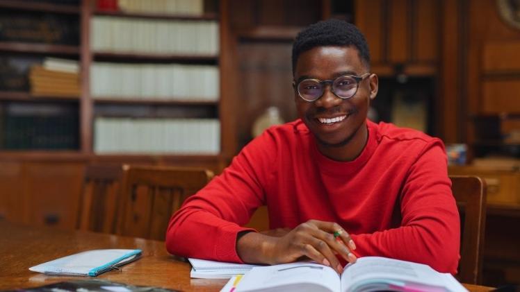 male student sitting with a book open